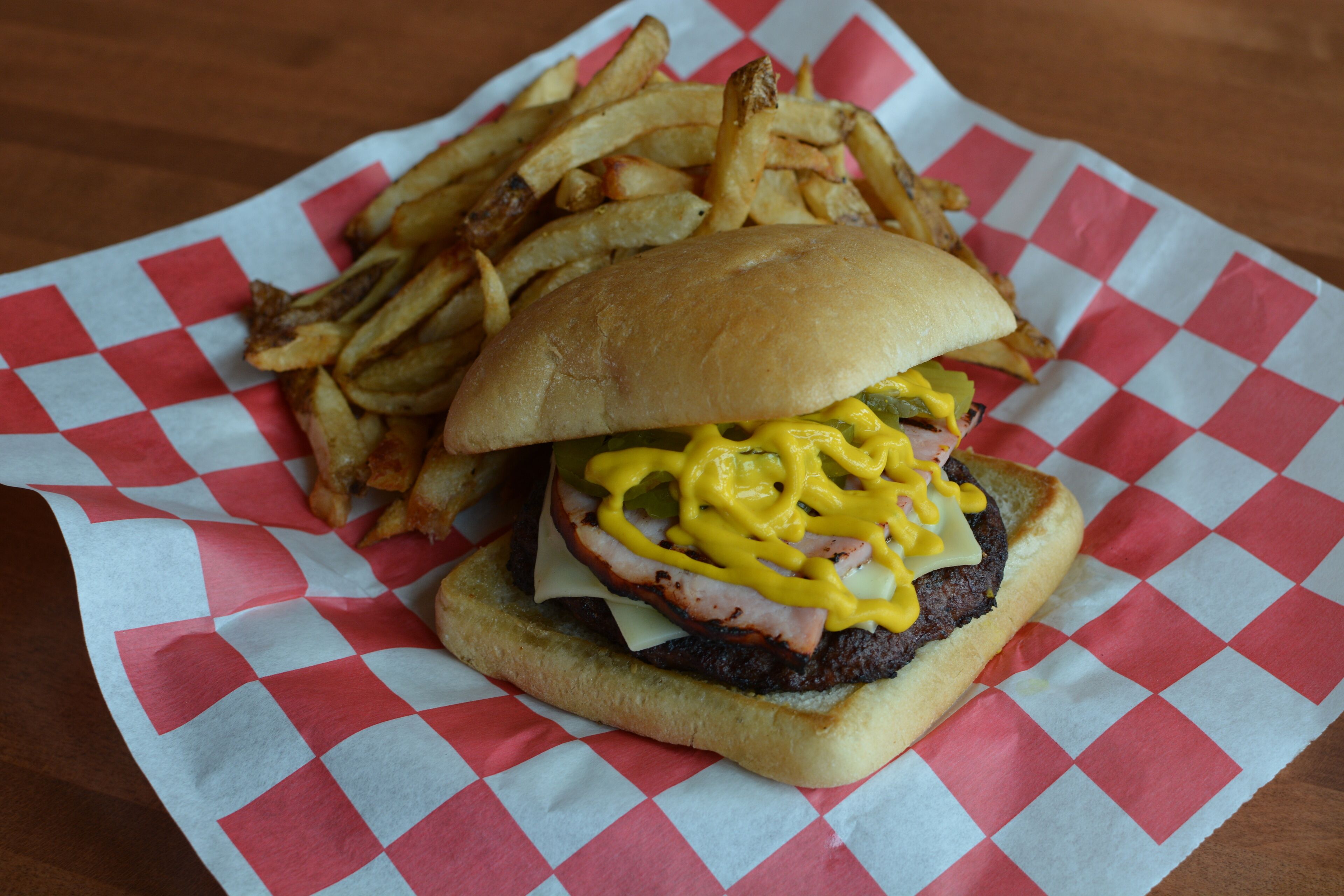 Una hamburguesa con papas fritas sobre un mantel de cuadros.