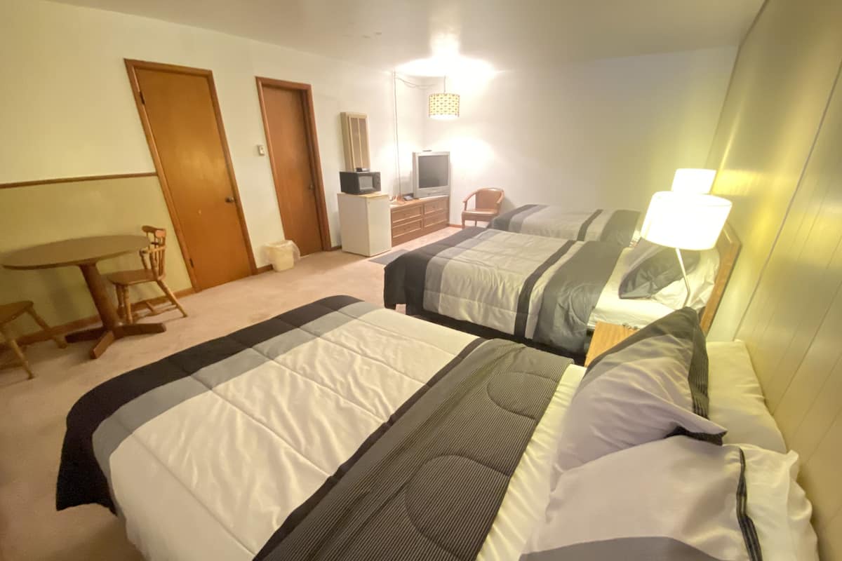Une chambre d’hôtel avec deux lits, un bureau, une chaise, une commode et un téléviseur.