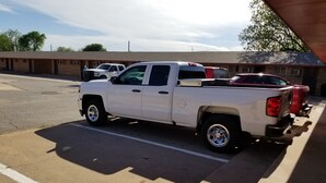 Una camioneta pickup blanca estacionada en un estacionamiento, con un edificio al fondo.