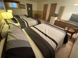 Une chambre d’hôtel avec deux lits, un bureau, une télévision et une chaise.