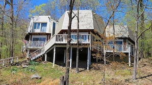 A cabin with a two-story structure, a covered porch, and a staircase leading to the upper level.