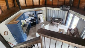A high-ceilinged kitchen with blue cabinets, a microwave, and a refrigerator.