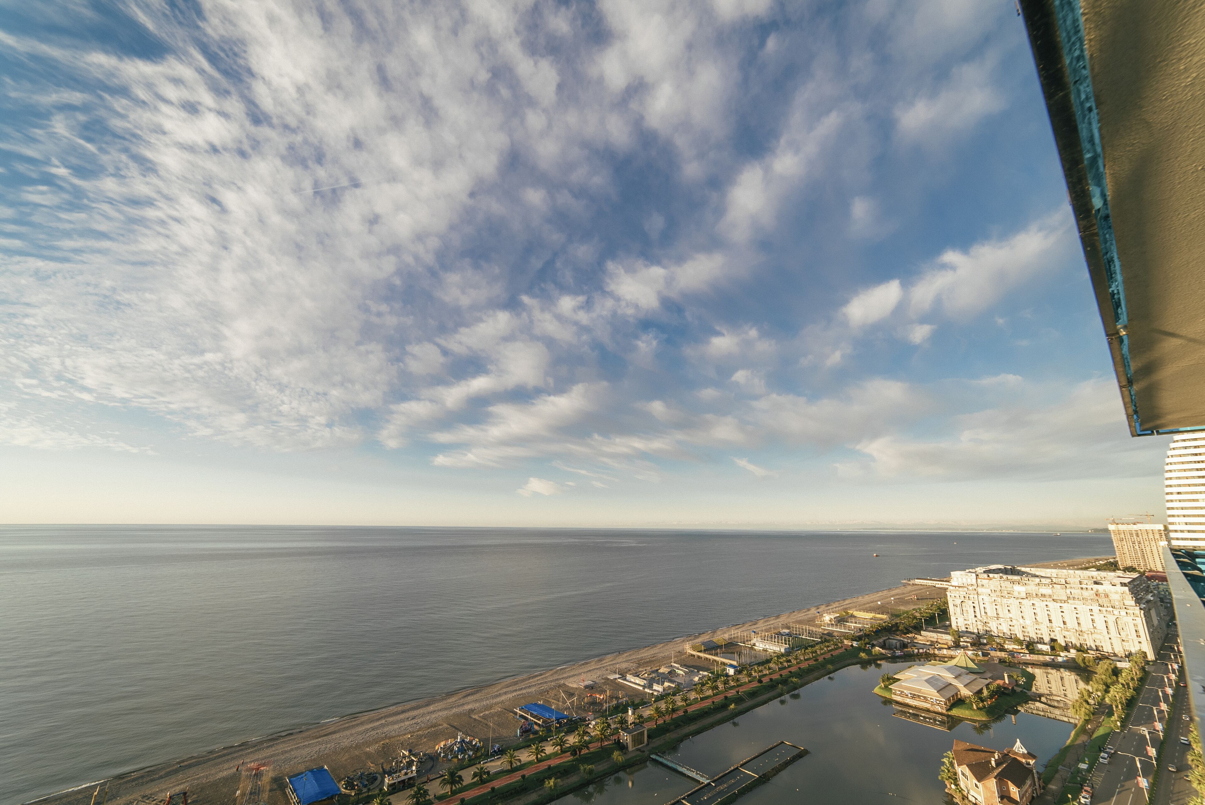 Vista aérea de una ciudad costera con un puerto deportivo, un hotel grande y una playa.