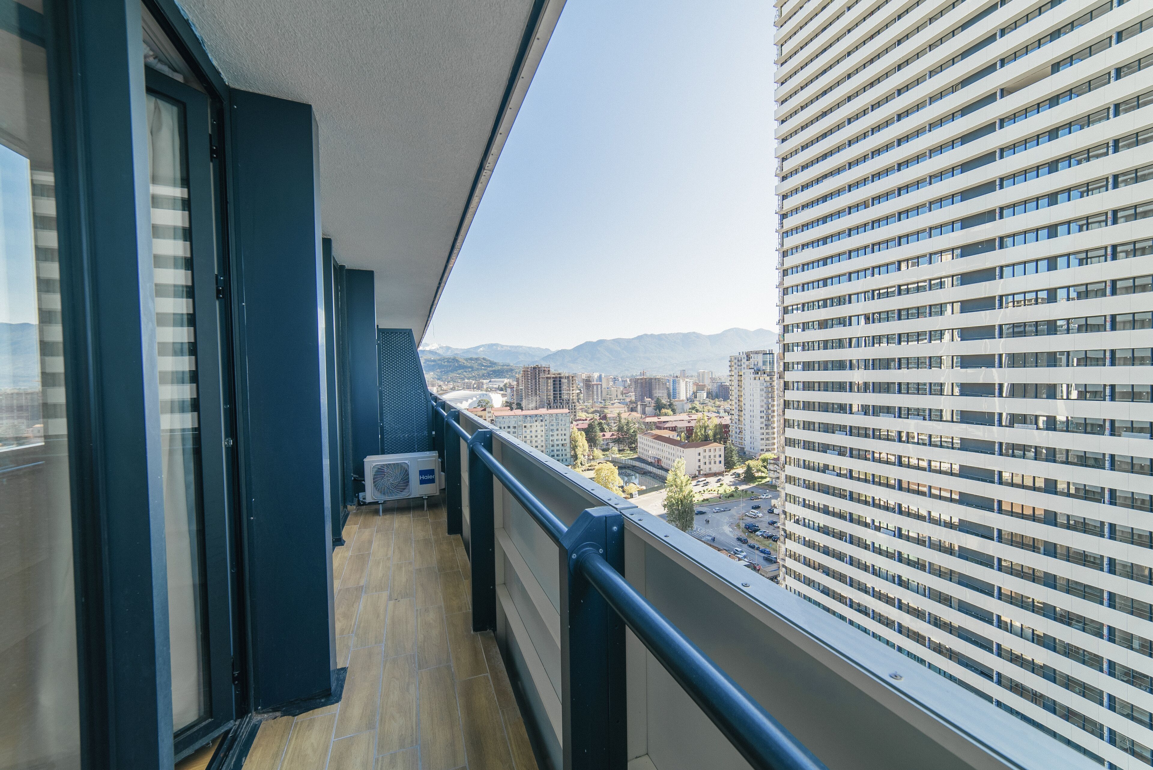 A balcony with a view of a cityscape, including buildings and mountains.