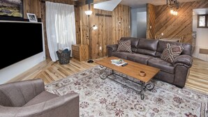 Ein gemütliches Wohnzimmer mit einem braunen Ledersofa, einem Holztisch und einem gemusterten Teppich.