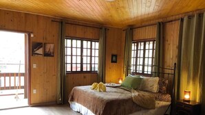 Una stanza in legno con un letto, un comodino e una finestra con tende.