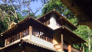 Una casa in legno a due piani con un balcone, un garage e un'auto parcheggiata.