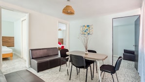 Uma sala de estar moderna com sofá, mesa de jantar, cadeiras e luminária pendente.