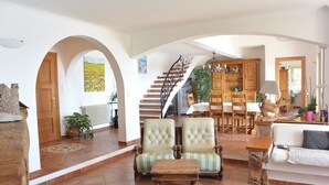 A spacious living area with a staircase, wooden furniture, and a view of the outdoors.
