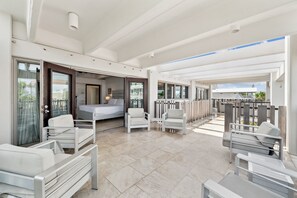 Un balcon spacieux avec un lit, deux fauteuils blancs et une table à manger.