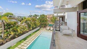 Un quartier résidentiel moderne doté d’une piscine, de palmiers et d’un balcon avec une chaise.