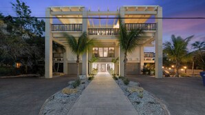 L’entrée d’un hôtel, avec un chemin central, des palmiers et une allée couverte.