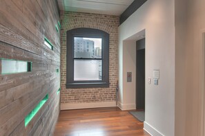 A hallway with a wooden wall, a window, and a door.