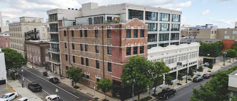 A multi-story building with a mix of brick and glass facades, located at a city intersection with visible street parking and crosswalks.