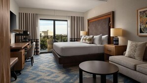 A hotel room with a bed, a desk, a sofa, a coffee table, and a TV.