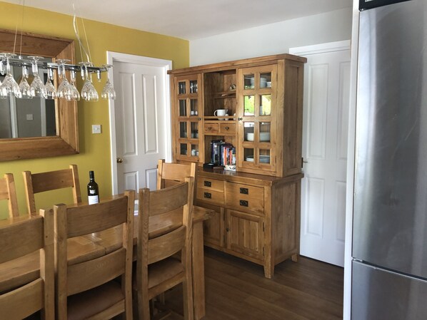 A kitchen with wooden cabinets, a dining table with chairs, a refrigerator, and a mirror on the wall. - Linmore, 3 bedroom, 2 bathroom detached holiday home, Aviemore. (Aviemore)