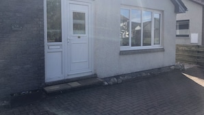 Ein Haus mit weißer Fassade, einer Haustür und einem Fenster.