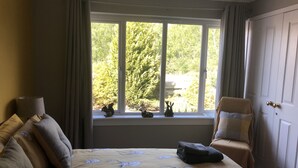 Ein Schlafzimmer mit großem Fenster, einem Bett mit Blumendekoration, einem Stuhl und einer Tür.