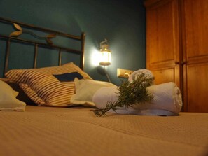 A neatly made bed with striped pillows, a rolled-up towel, and a sprig of greenery. - 1º-APT-CASA ANGELITA (Olocau Del Rey)
