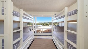 A compact, multi-level bunk room with a view of the outdoors. - MANYANA | Accom Holidays (WAMBERAL)