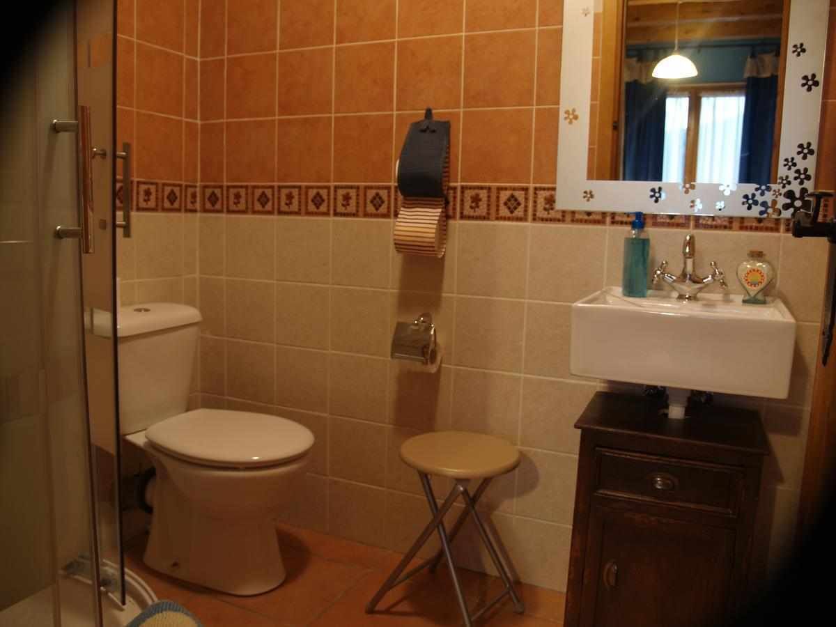 Een badkamer met toilet, een klein krukje, een wastafel en een spiegel.