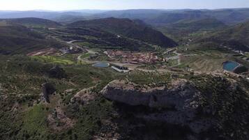 A mountainous landscape with terraced fields, a small settlement, and a large rock formation.