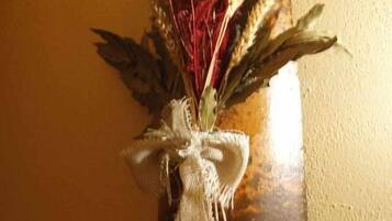 Decoración rústica montada en la pared con plantas secas y un lazo de arpillera.