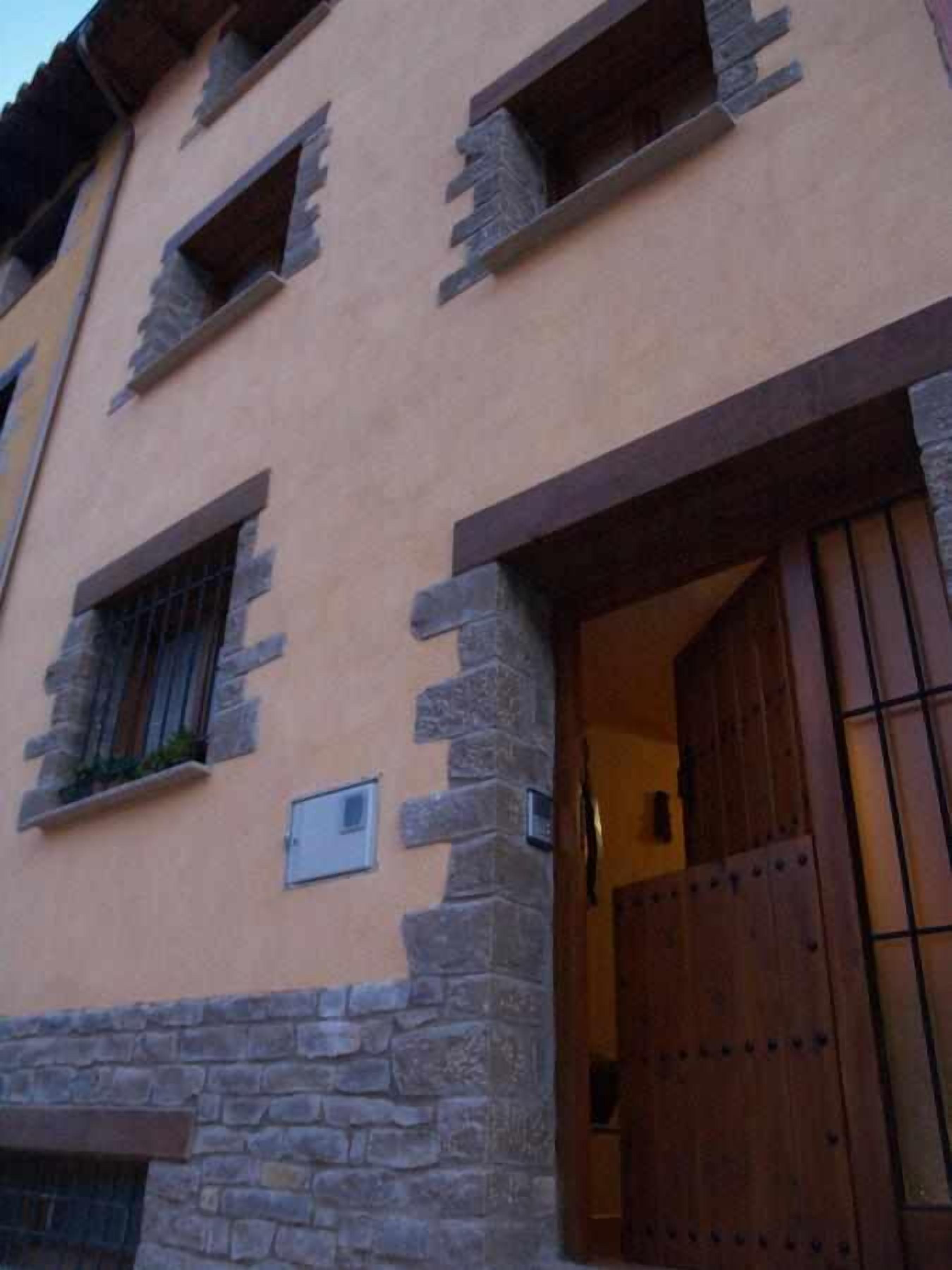 Ein Gebäude mit Außenwänden aus Stein und Putz, einer Holztür mit Metallgittern und einem kleinen Fenster mit einem Metallgitter.
