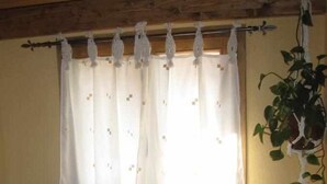 A room with a window covered by a white curtain with floral patterns, a wooden chair, and a potted plant. - LILA-ROOM-Rural House Angelita (Olocau Del Rey)