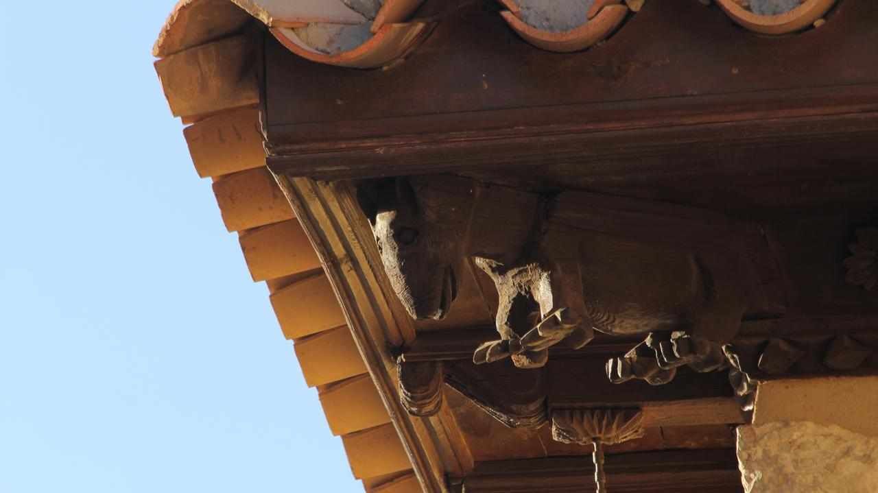 En närbild på ett tak med terrakottafärgade takpannor och utsmyckade metallarbeten.