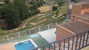 Una piscina amb una zona de solàrium al voltant, una tanca i vistes al paisatge circumdant.