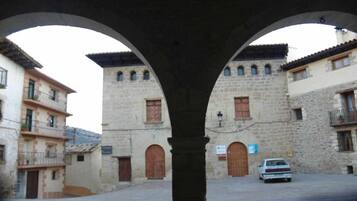 A stone building with arched doorways and a car parked in front.