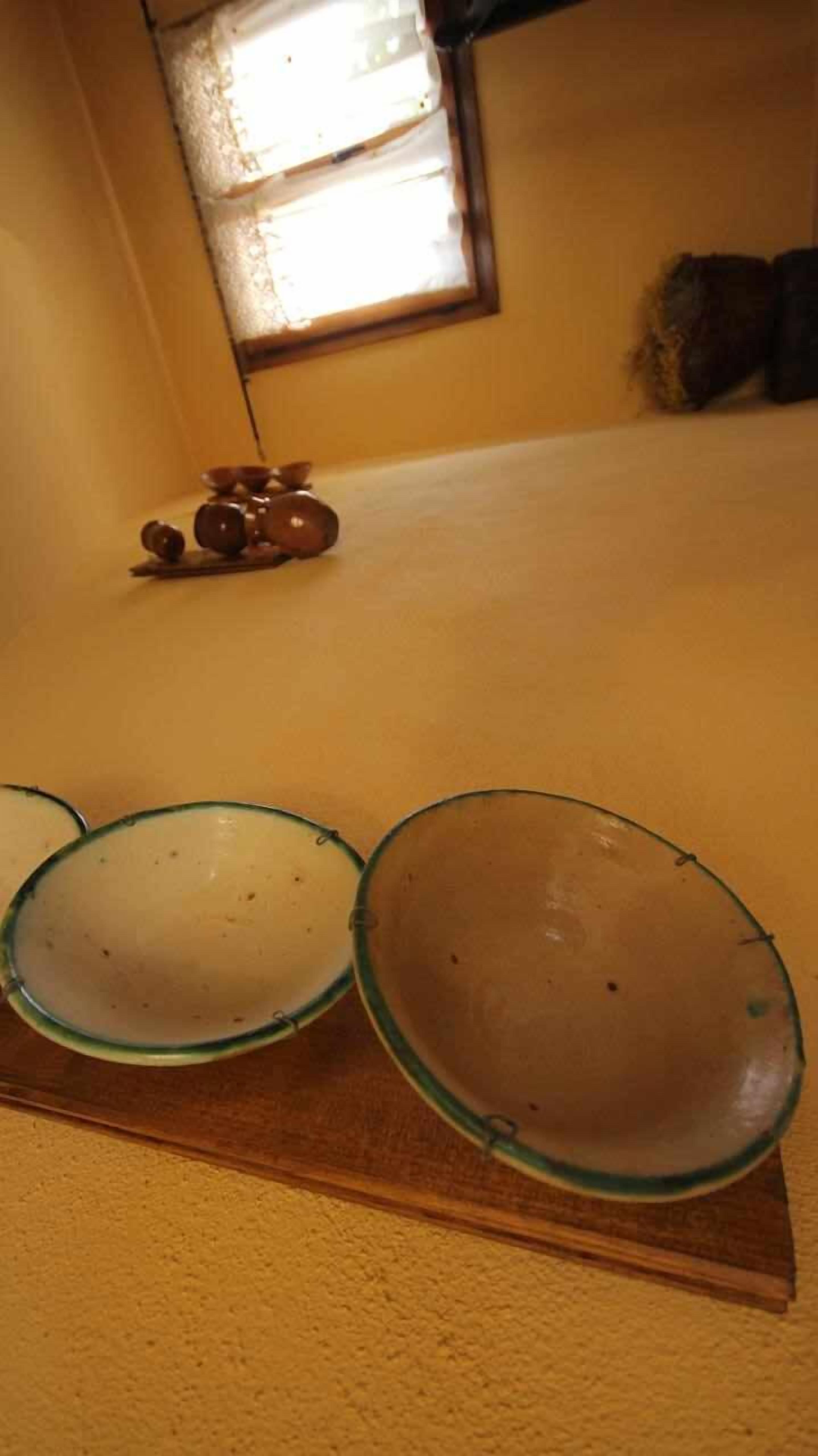 Una cocina con encimera de madera, tres cuencos de vidrio y una ventana al fondo.