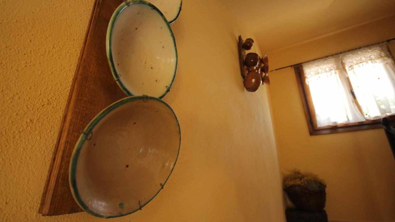 Une pièce avec deux grands bols posés sur une étagère en bois, un luminaire fixé au mur et une fenêtre avec des rideaux.