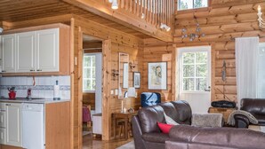 A spacious cabin interior with a wooden interior, a kitchen area, a dining space, and a living room with leather sofas.