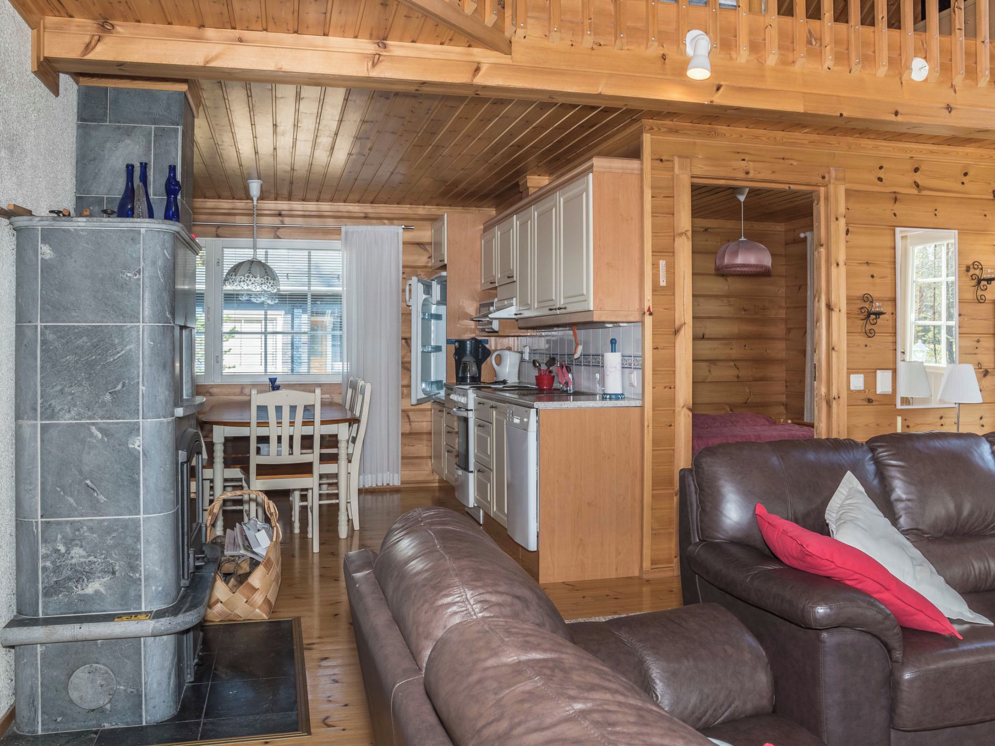 Interior acogedor de una cabaña con chimenea de piedra, techo de madera y sofá de cuero.