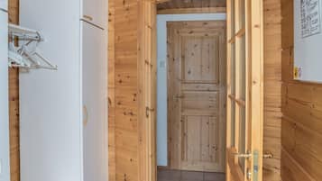 A wooden interior with a white door, a white wall-mounted drying rack, and a tiled floor.
