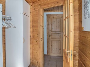 A wooden interior with a white door, a white wall-mounted drying rack, and a tiled floor. - Koskelo by Interhome (Äkäslompolo)
