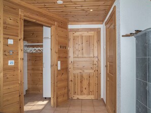 Un pasillo con paredes de madera y suelo de baldosas, que conduce a una puerta con picaporte.