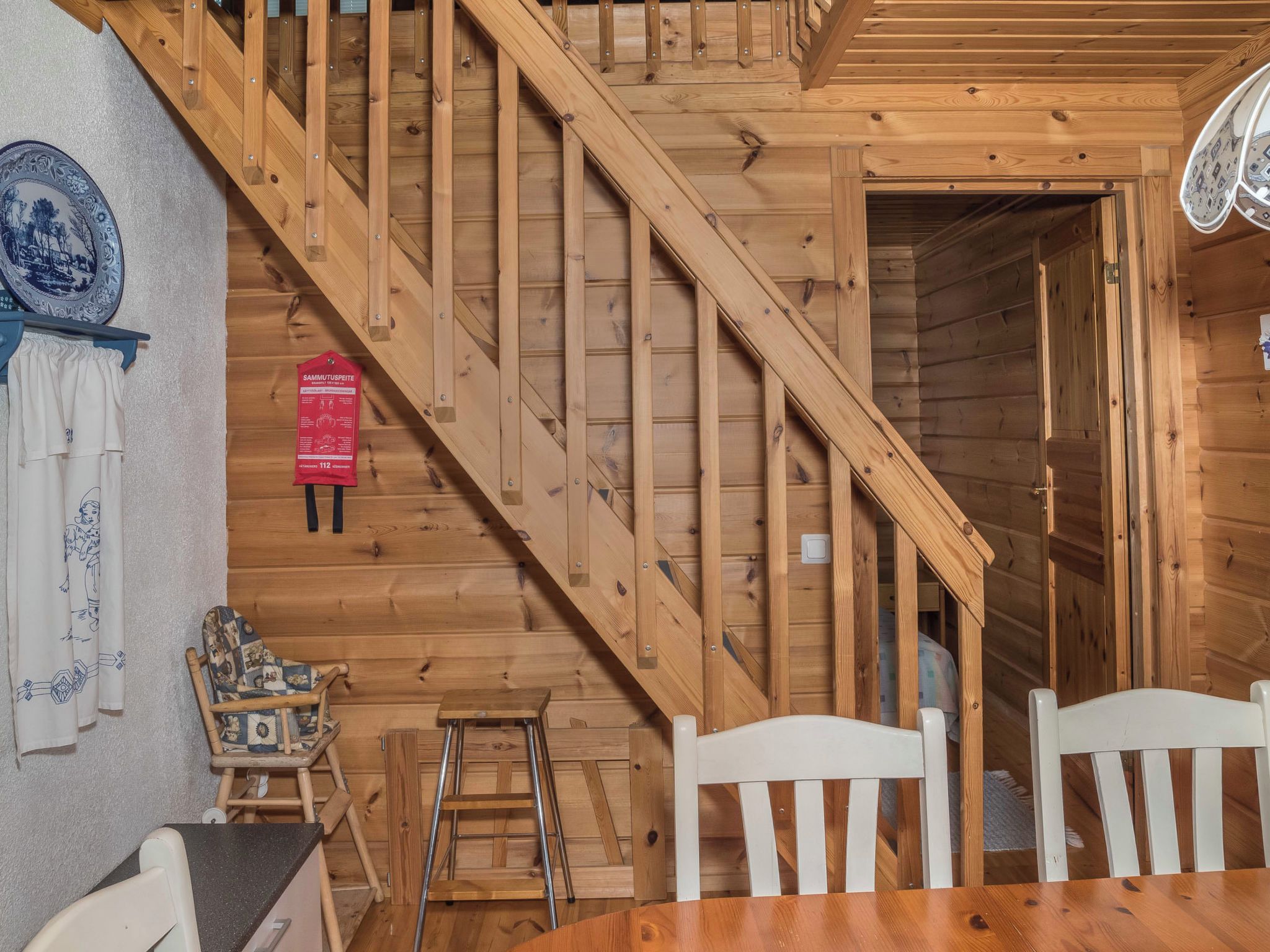 Un interior de madera con una escalera, una mesa de comedor, sillas y una pequeña escalera de mano.