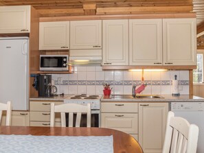 A compact kitchen with white cabinets, a microwave, a coffee maker, and a dishwasher. - Koskelo by Interhome (Äkäslompolo)