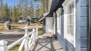 A wooden deck with a white railing leading to a house with a dark exterior and white trim.