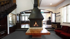 Een modern interieur met een centraal gelegen open haard, een trap en een rode bank.