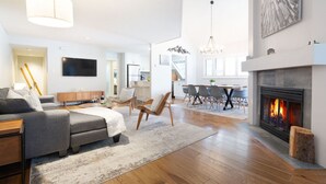 A modern living room with a fireplace, a dining area, and a kitchen in the background. - Luxury 3BR/2BA-1700 sq ft, Mountain view,BBQ (Whistler)