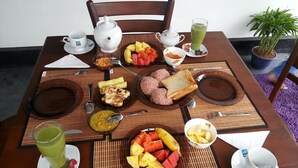 Une table de petit-déjeuner avec divers aliments, notamment des fruits, du pain et un smoothie vert.