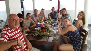 Un groupe de personnes est assis autour d’une table, devant divers plats et boissons.