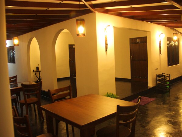 A dining area with a wooden table and chairs, a small plant, and a door with a number.