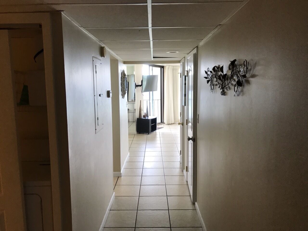 Ein Korridor mit Fliesenboden, ebener Decke und einer Tür auf der rechten Seite.