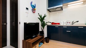 Eine moderne Küche mit dunkelblauen Schränken, einem Flachbildfernseher, einer Kaffeemaschine und einem roten Topf auf der Arbeitsfläche.