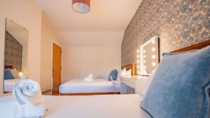 Ett hotellrum med en säng, ett skrivbord, en spegel med belysning och en vägg med ett mönster.
